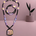 Necklace with colorful beads and a decorative pendant on a pink background