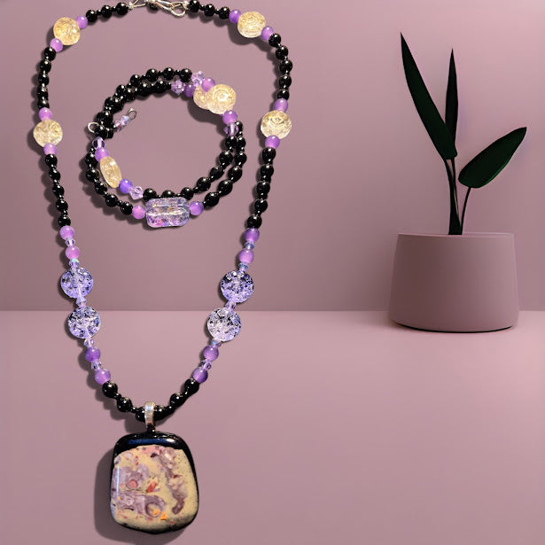 Necklace with colorful beads and a decorative pendant on a pink background