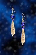 Gold and blue teardrop earrings on a blue background