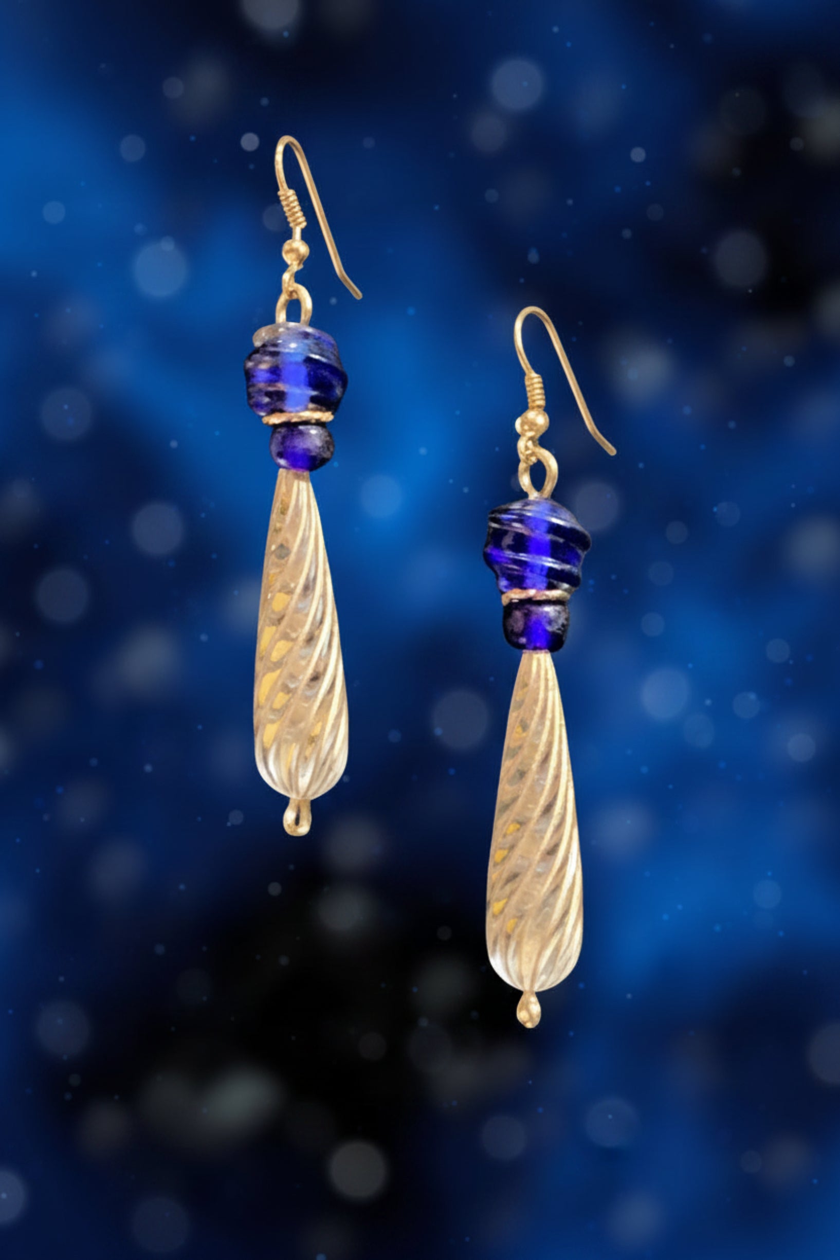 Gold and blue teardrop earrings on a blue background
