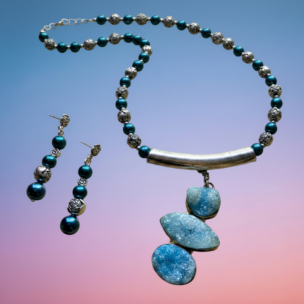 A Heartfelt Creations hand-crafted  jewelry set featuring a necklace and matching drop earrings. The necklace has dark teal beads, textured silver beads, a polished silver bar, and three stacked blue agate pendants.
