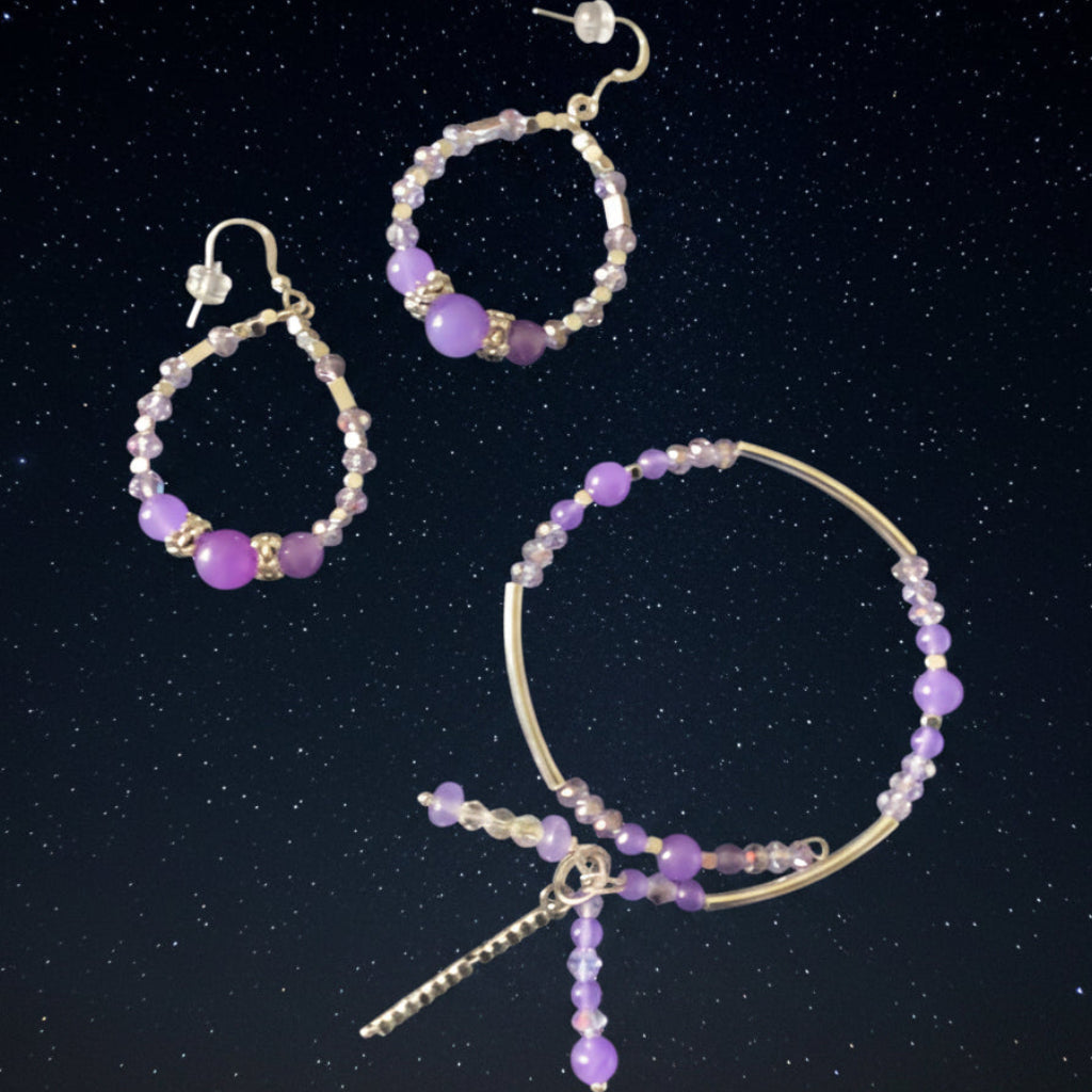 Handcrafted jewelry set featuring a purple agate teardrop pendant necklace, matching beaded hoop earrings, and a beaded charm bracelet with dangling silver accents against a clean white background