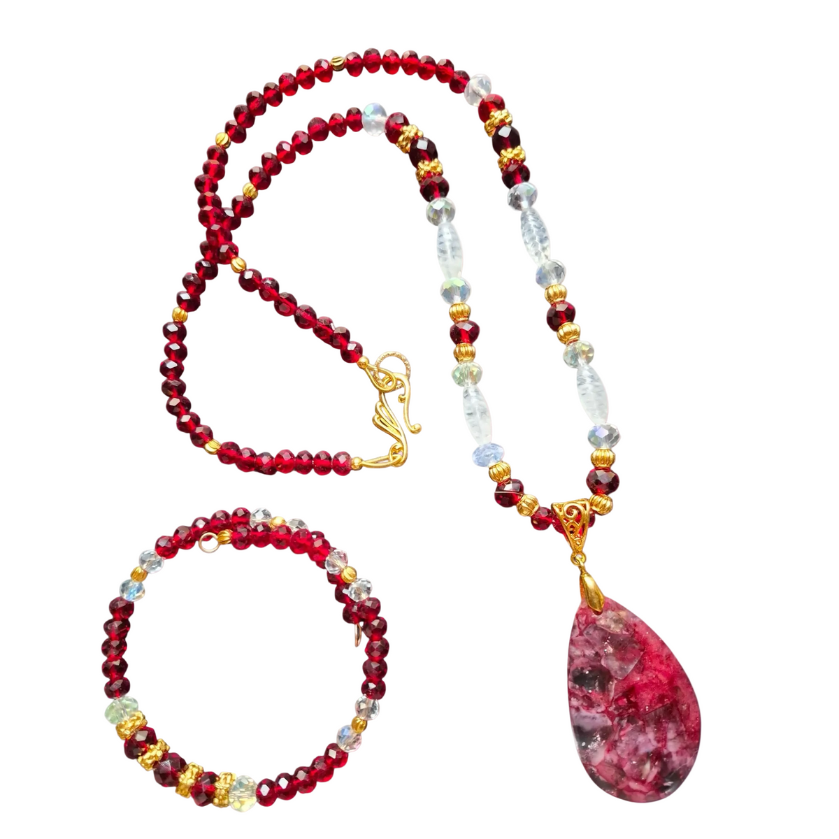 Heartfelt Creations is proud to offer a handmade jewelry set featuring a necklace and bracelet, both crafted from small, faceted red garnet beads and light blue, clear, and gold-colored beads, with the necklace having a large, teardrop-shaped red and white marbled agate  stone pendant suspended from a gold-toned bail and a matching gold-toned clasp