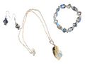 A jewelry set featuring a silver-tone chain necklace with a large iridescent shell pendant, matching drop earrings, and a beaded bracelet with blue and clear faceted beads, displayed on a solid white background.