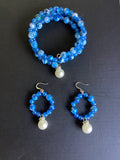 Blue beaded bracelet and earrings with pearl drops on a black background