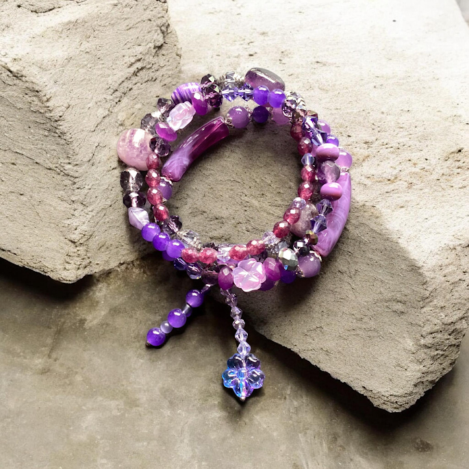 Multicolored beaded bracelet with a crystal pendant on a stone surface