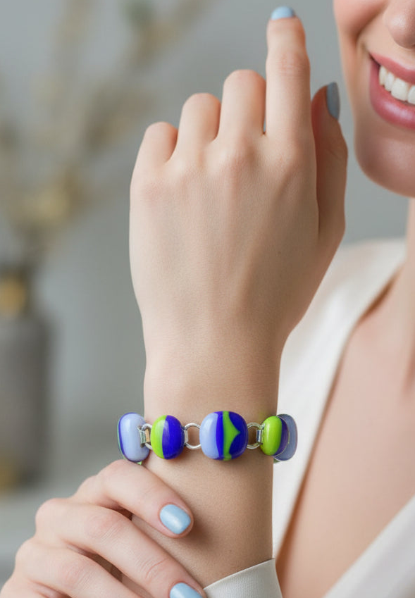 A close-up of a woman's wrist wearing a colorful beaded bracelet with blue, purple, green, and white round beads separated by small silver rings.
