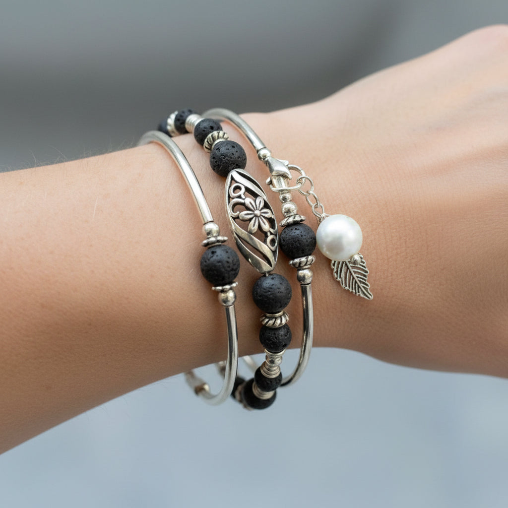 Stack of silver and black beaded bracelets on a purple textured background