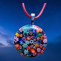 Colorful floral-patterned pendant on a red cord against a night sky background