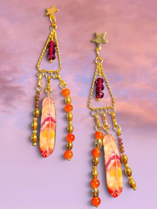 Pair of gold earrings with colorful beads on a pinkish-purple gradient background