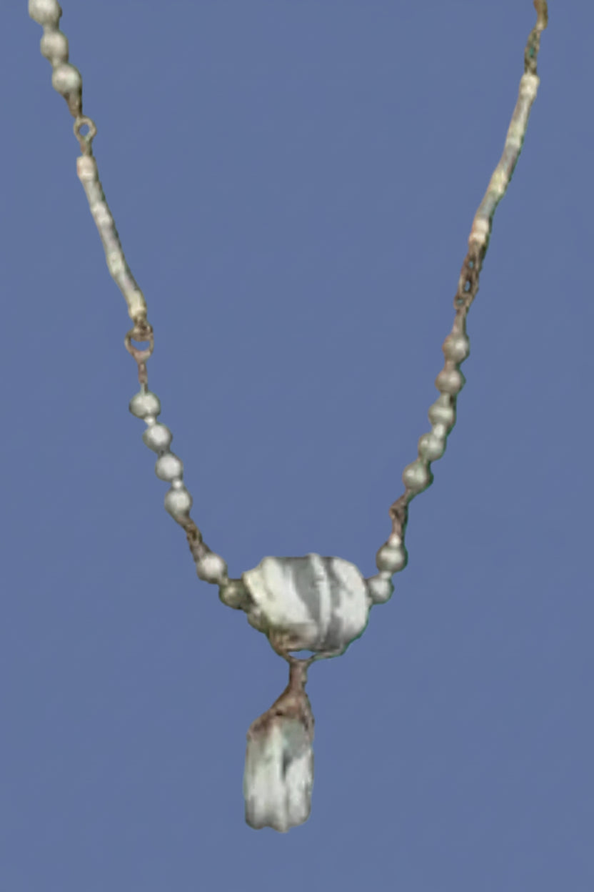 Necklace with beads and a pendant on a green background