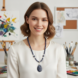 a handmade jewelry set featuring a necklace and a bracelet, both crafted from small, polished, dark blue sodalite beads, with the necklace additionally adorned with two larger, striped agate beads and a prominent teardrop-shaped dark blue agate pendant with white veining, all connected by a sterling silver clasp and decorative bail.