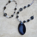 Heartfelt Creations handcrafted necklace and bracelet set with a dark agate pendant, black floral beads, and crystals.
