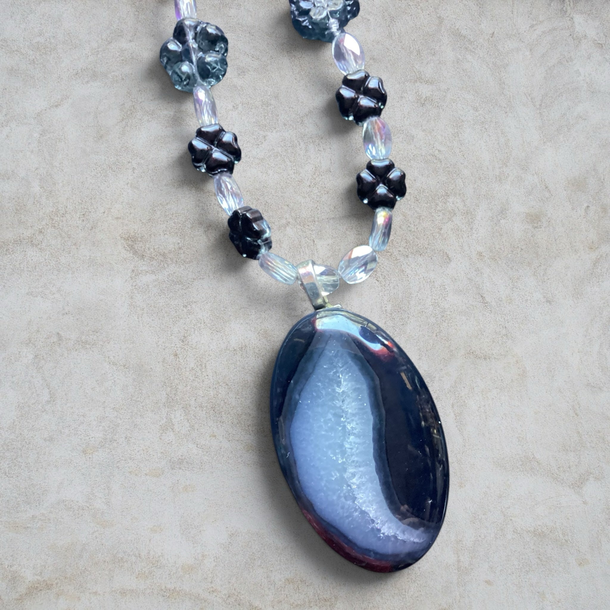 Heartfelt Creations handcrafted necklace featuring a dark agate geode pendant with black floral glass and crystal beads.