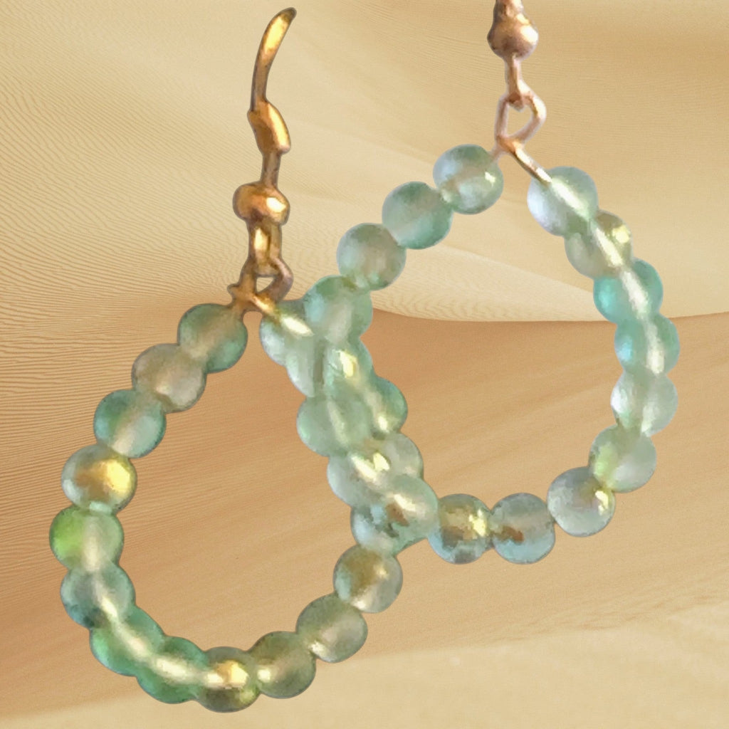 Heartfelt Creations Lumina aqua sea-foam green beaded hoop earrings with gold-tone hooks on a soft fabric background.