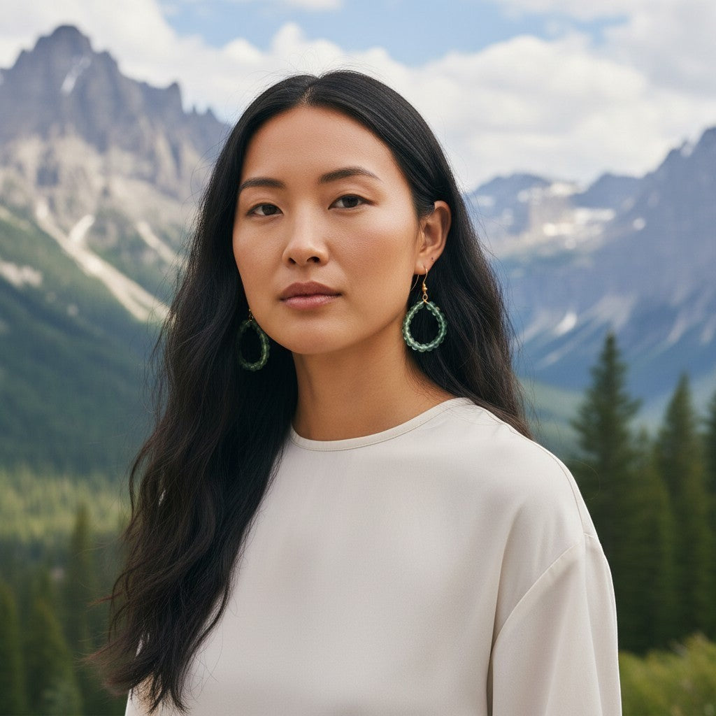 Heartfelt Creations Lumina aqua beaded hoop earrings worn by a woman against a scenic mountain landscape.