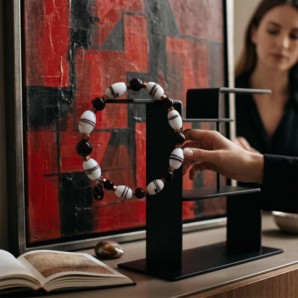 Heartfelt Creations beaded bracelet with black and striped white beads and a silver dolphin charm on a display stand.