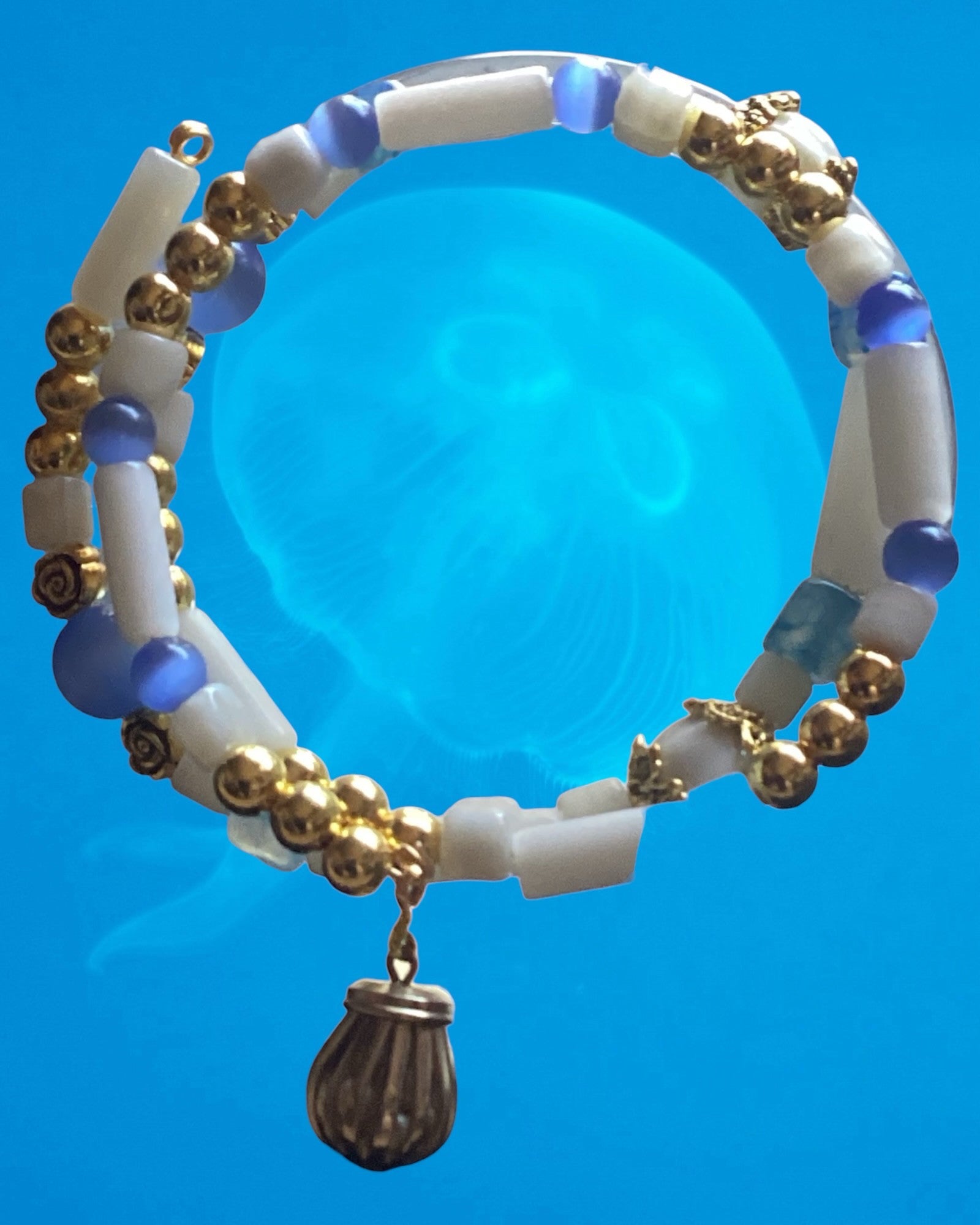 Heartfelt Creations beaded bracelet with white cylindrical beads, blue accents, and gold-tone spacers with a charm.