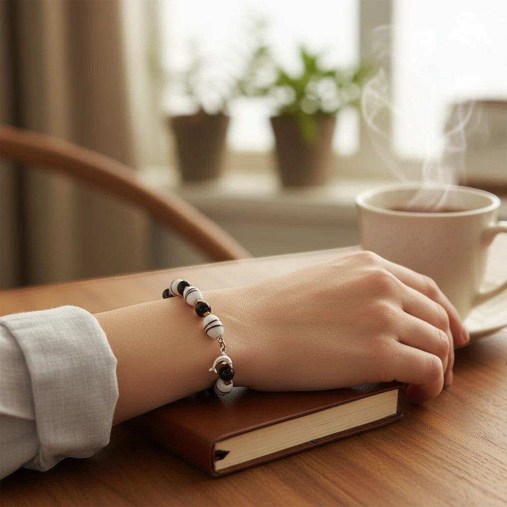 Heartfelt Creations beaded bracelet with black and white striped beads and a silver dolphin charm on a woman's wrist.