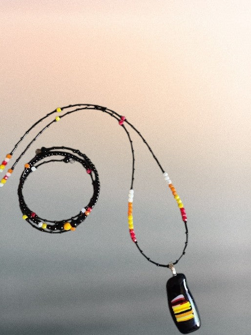 Heartfelt Creations handcrafted jewelry set with a black fused glass pendant necklace and matching beaded wrap bracelet.