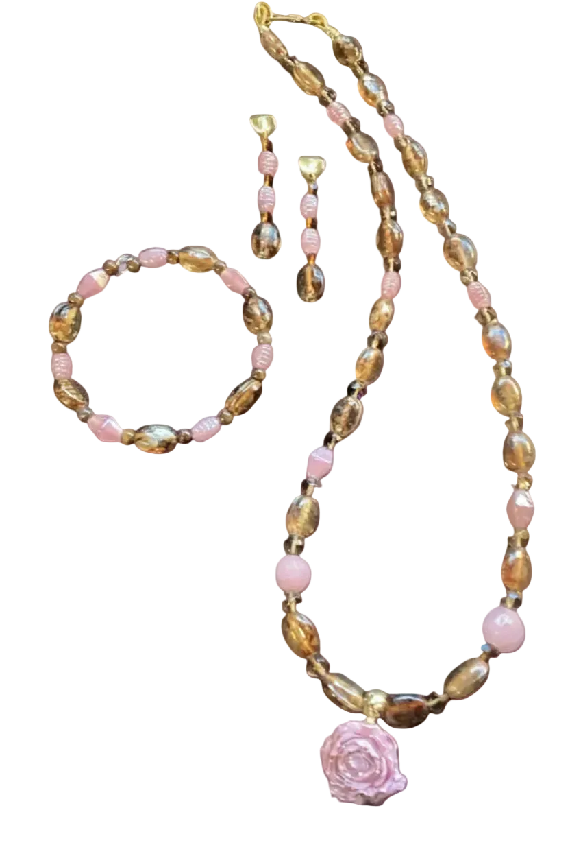 Heartfelt Creations design of a vintage-style jewelry set consisting of a necklace, bracelet, and earrings, all featuring a mix of translucent amber-colored glass beads and opaque pale pink beads, with the necklace having a large, carved pink rose pendant and the earrings being a dangling design with a single amber and pink bead.