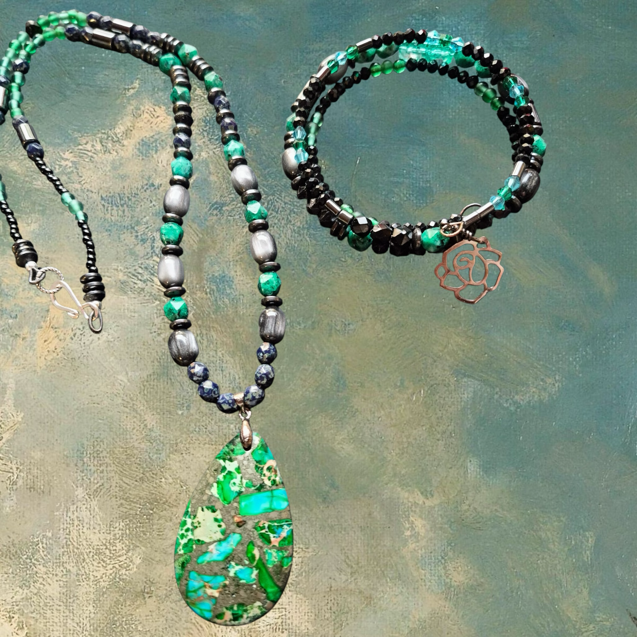 Heartfelt Creations artisan beaded necklace and bracelet set with pendant. Green, blue, and hematite beads with a teardrop pendant and rose charm.
