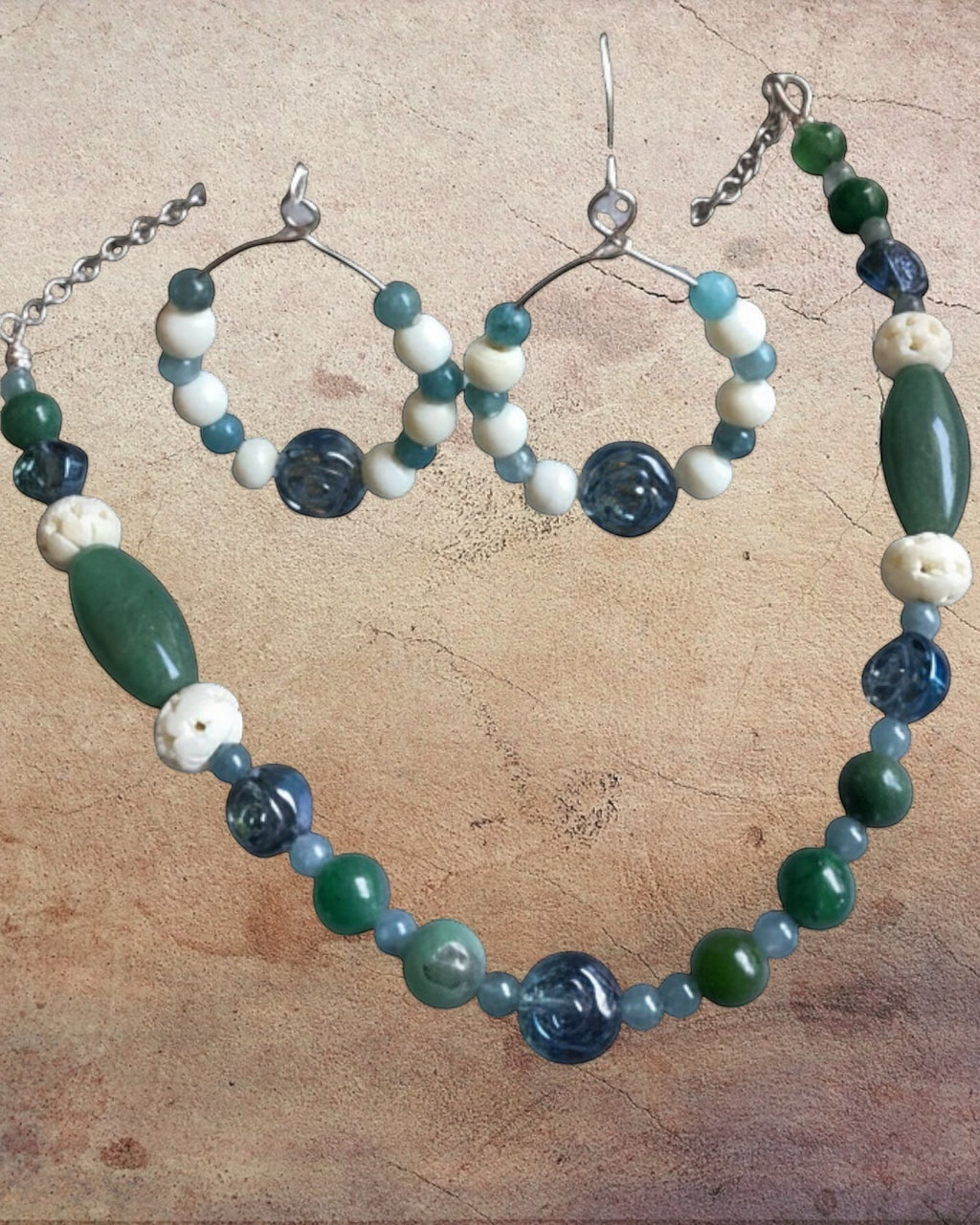 Heartfelt Creations artisan beaded jewelry set featuring a necklace and hoop earrings in green, blue, and off-white.
