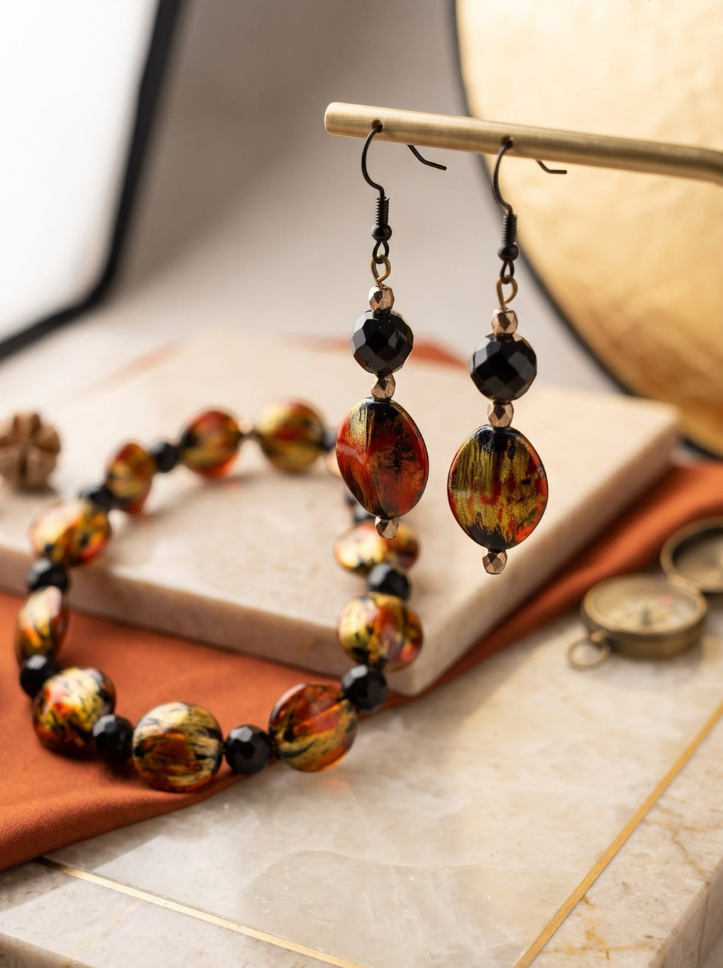 Heartfelt Creations artisan jewelry set featuring a beaded bracelet and drop earrings with fiery red and gold beads.