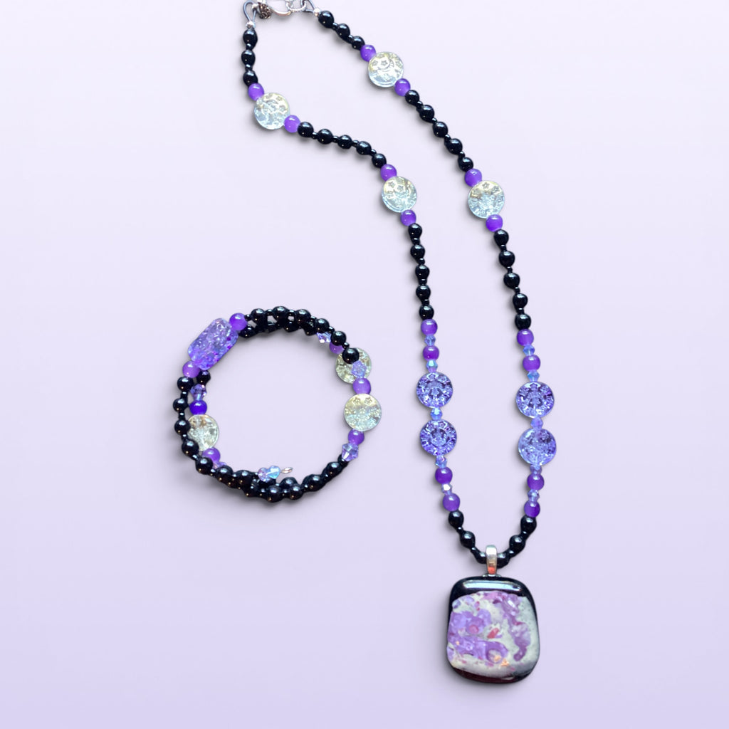 Heartfelt Creations handcrafted beaded necklace and bracelet set with black and purple glass beads and abstract pendant.