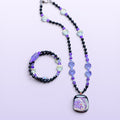Heartfelt Creations handcrafted beaded necklace and bracelet set with black and purple glass beads and abstract pendant.