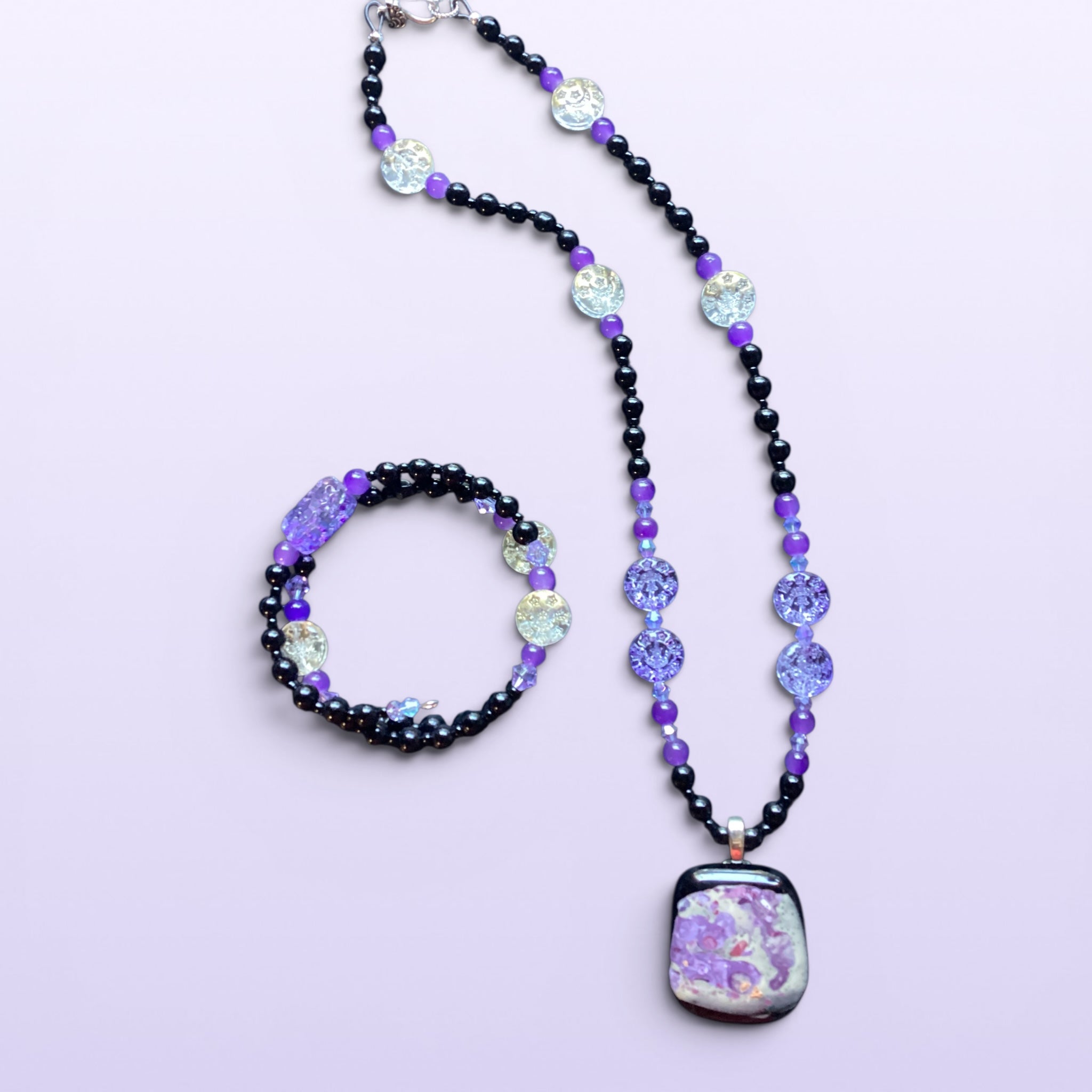Heartfelt Creations handcrafted beaded necklace and bracelet set with black and purple glass beads and abstract pendant.