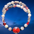 Heartfelt Creations handcrafted memory wire bracelet with crimson red, clear, and charcoal glass beads on blue sky