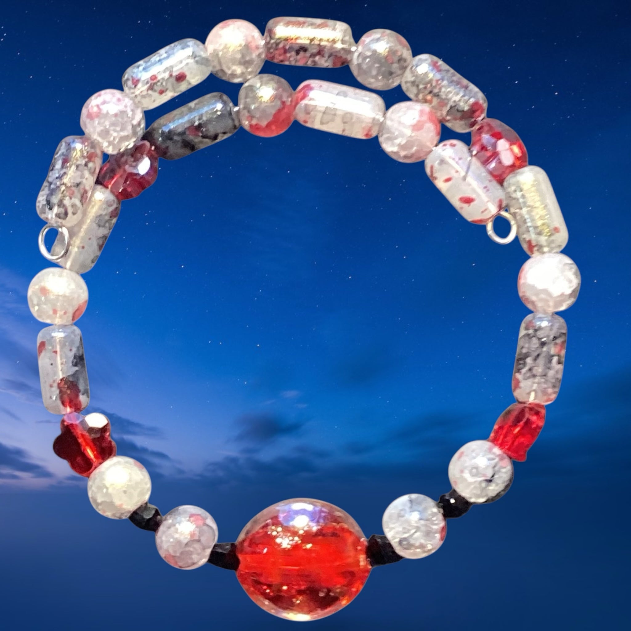 Heartfelt Creations handcrafted memory wire bracelet with crimson red, clear, and charcoal glass beads on blue sky