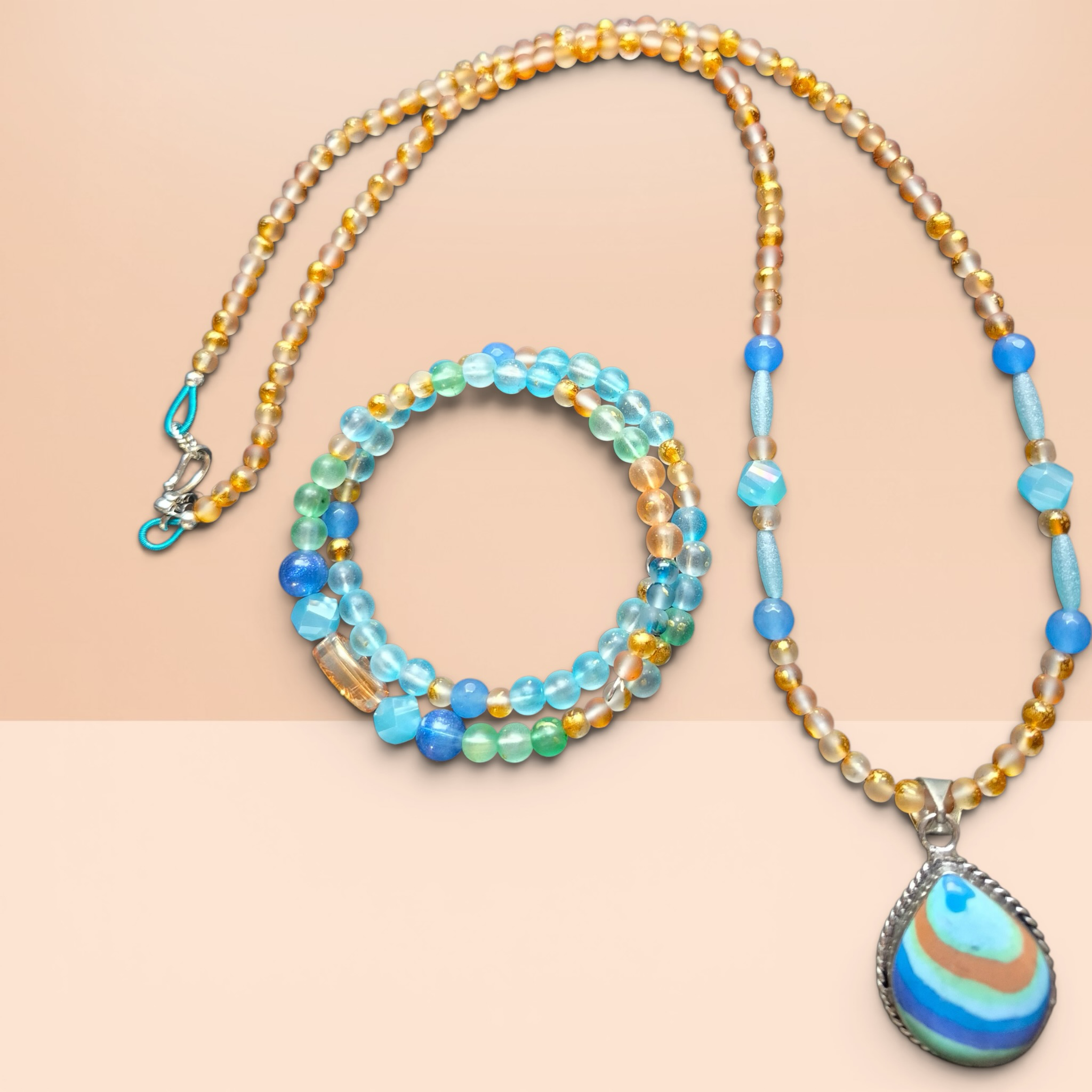 Heartfelt Creations beaded necklace and bracelet set with teardrop pendant in ocean blues, sandy oranges, and earthy greens.