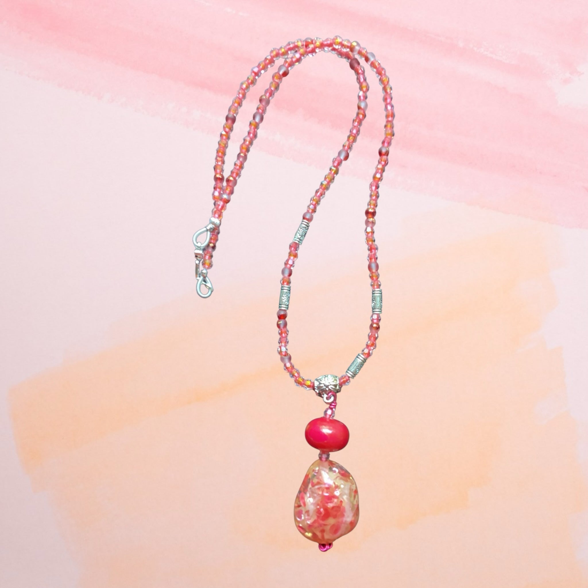 Heartfelt Creations handcrafted beaded necklace with pink and coral seed beads, silver spacers, and a glass pendant.