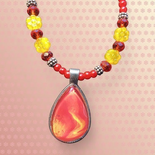 This is a jewelry set featuring a beaded necklace with a handmade, artfully designed piece of art under a glass dome teardrop pendant!!!   A matching beaded bracelet, and a pair of drop earrings complete the design of " wearable artwork".   The  beads are primarily red and yellow glass flowers  with silver-toned metal spacers and hooks.