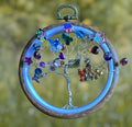 Heartfelt Creations beaded Tree of Life ornament with silver wire, colorful glass beads, crystals, and wooden hoop with blue glow.