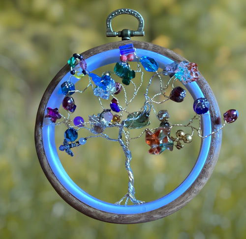 Heartfelt Creations beaded Tree of Life ornament with silver wire, colorful glass beads, crystals, and wooden hoop with blue glow.