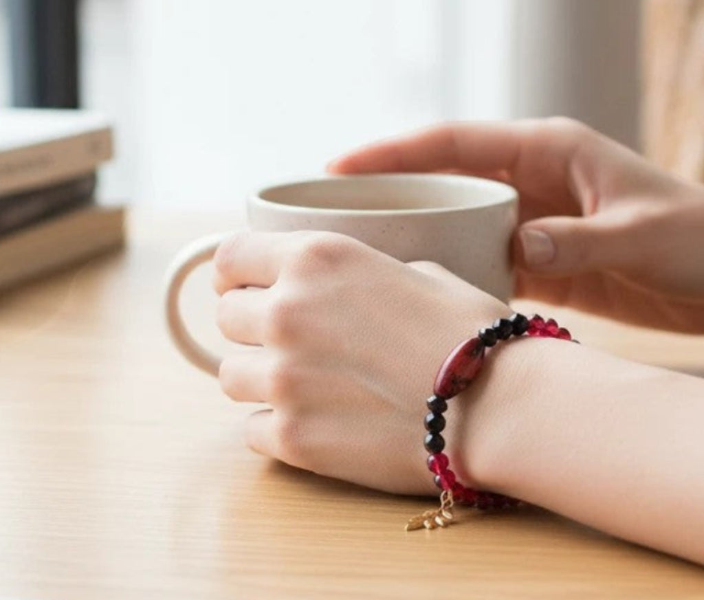 Heartfelt Creations beaded wire-wrap bracelet with crimson and black beads and a gold leaf charm worn on a wrist