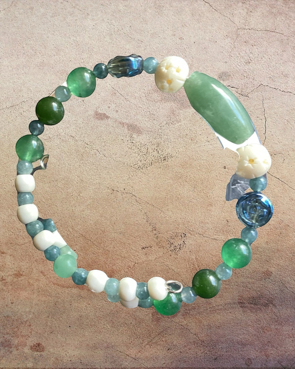 Heartfelt Creations artisan wrap bracelet featuring green stones, floral-carved beads, and blue glass accents.