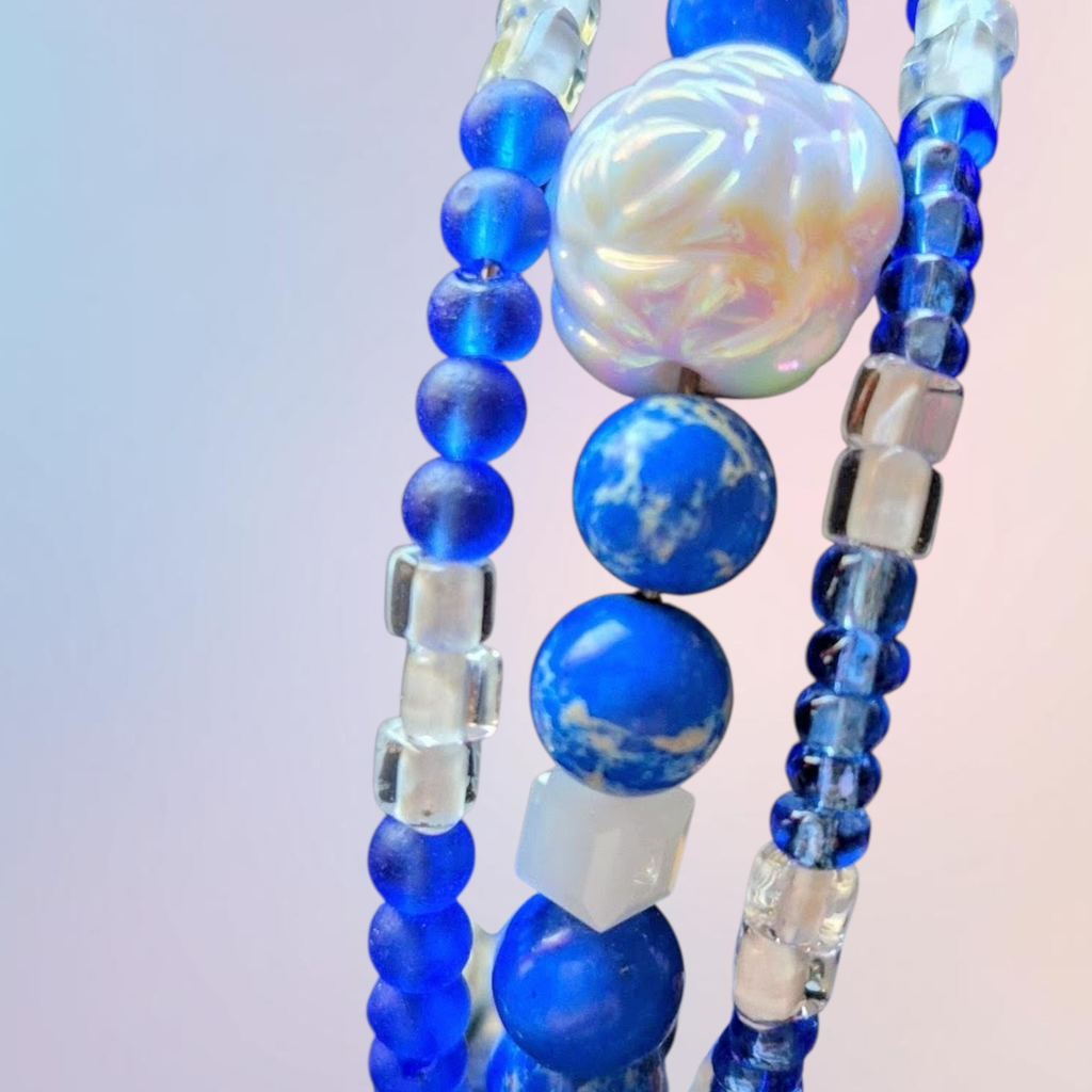 Heartfelt Creations blue beaded bracelet stack with flower charm, clear square beads, and marbled blue stones.