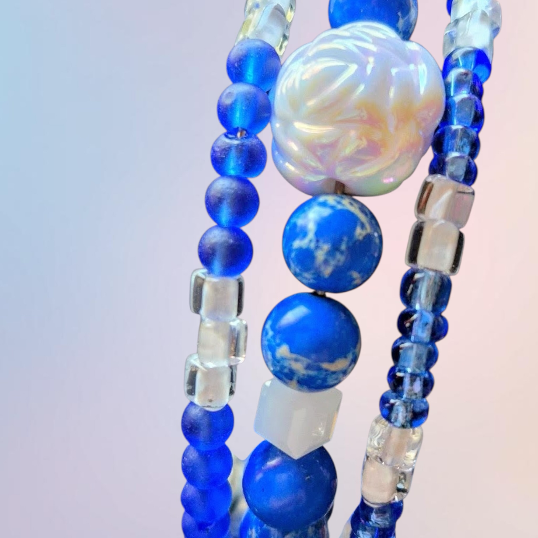 Heartfelt Creations blue beaded bracelet stack with flower charm, clear square beads, and marbled blue stones.