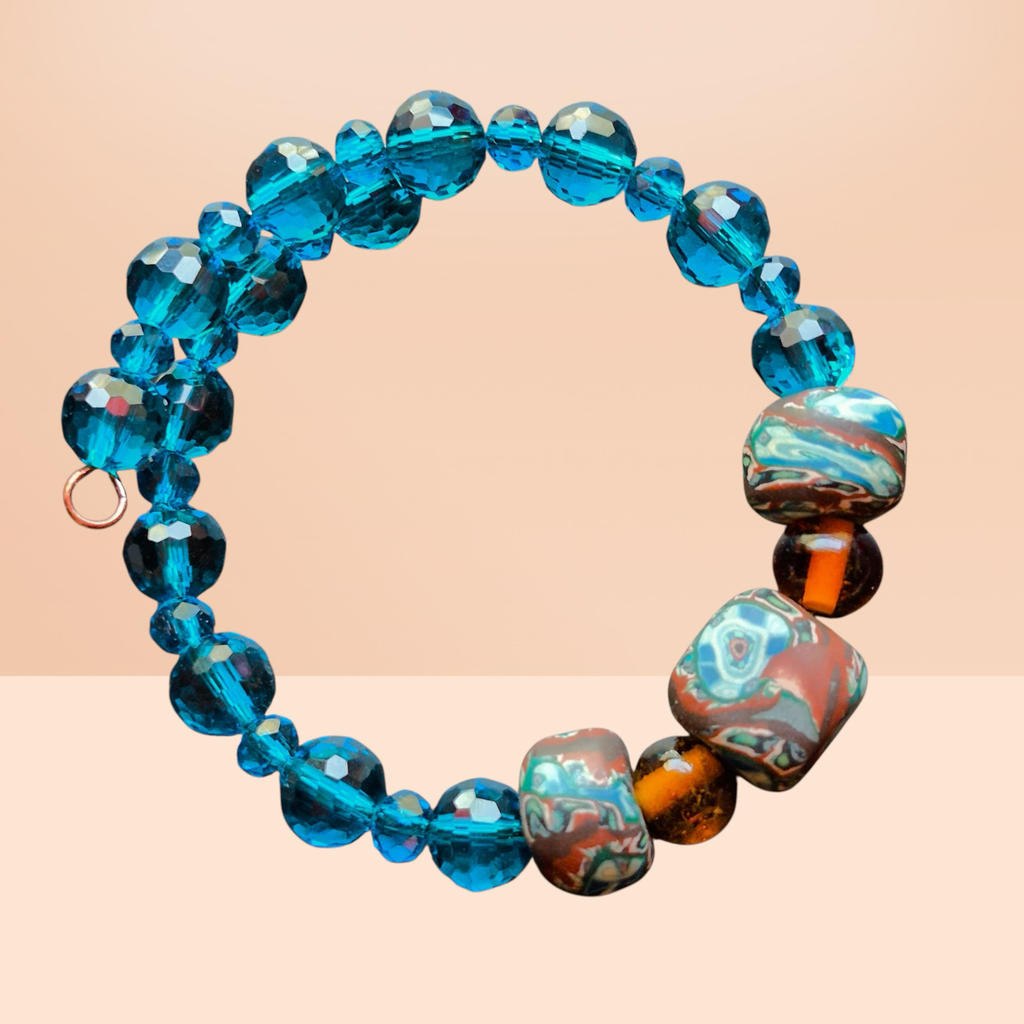 Heartfelt Creations handmade coil bracelet with faceted blue glass beads and unique marbled polymer clay accent beads.