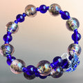 Heartfelt Creations stretch bracelet with royal blue glass beads, metallic-flecked spheres, and a butterfly charm.