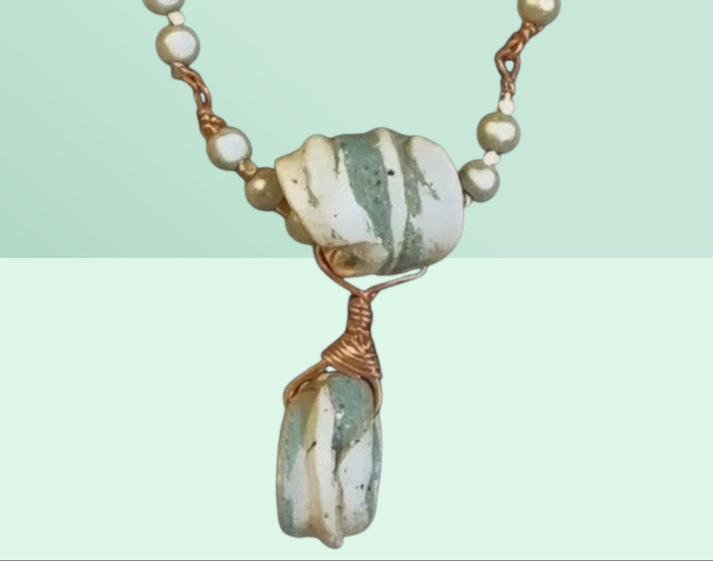 Heartfelt Creations handcrafted necklace with grey pearlescent beads, striped ceramic pendant, and copper wire wrap.