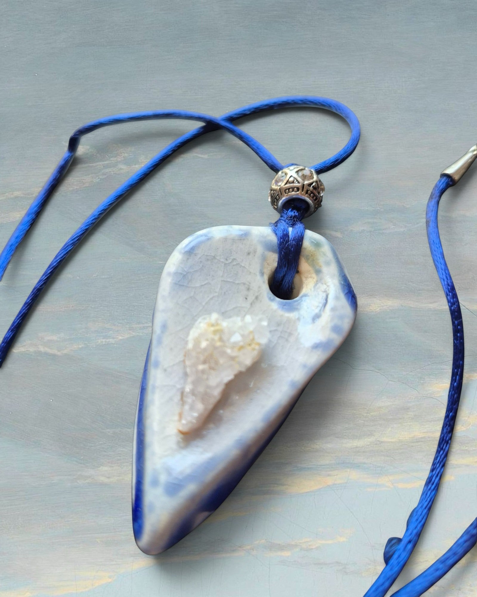 Heartfelt Creations artisan ceramic pendant necklace with blue crackle glaze, raw crystal, and blue silk cord.