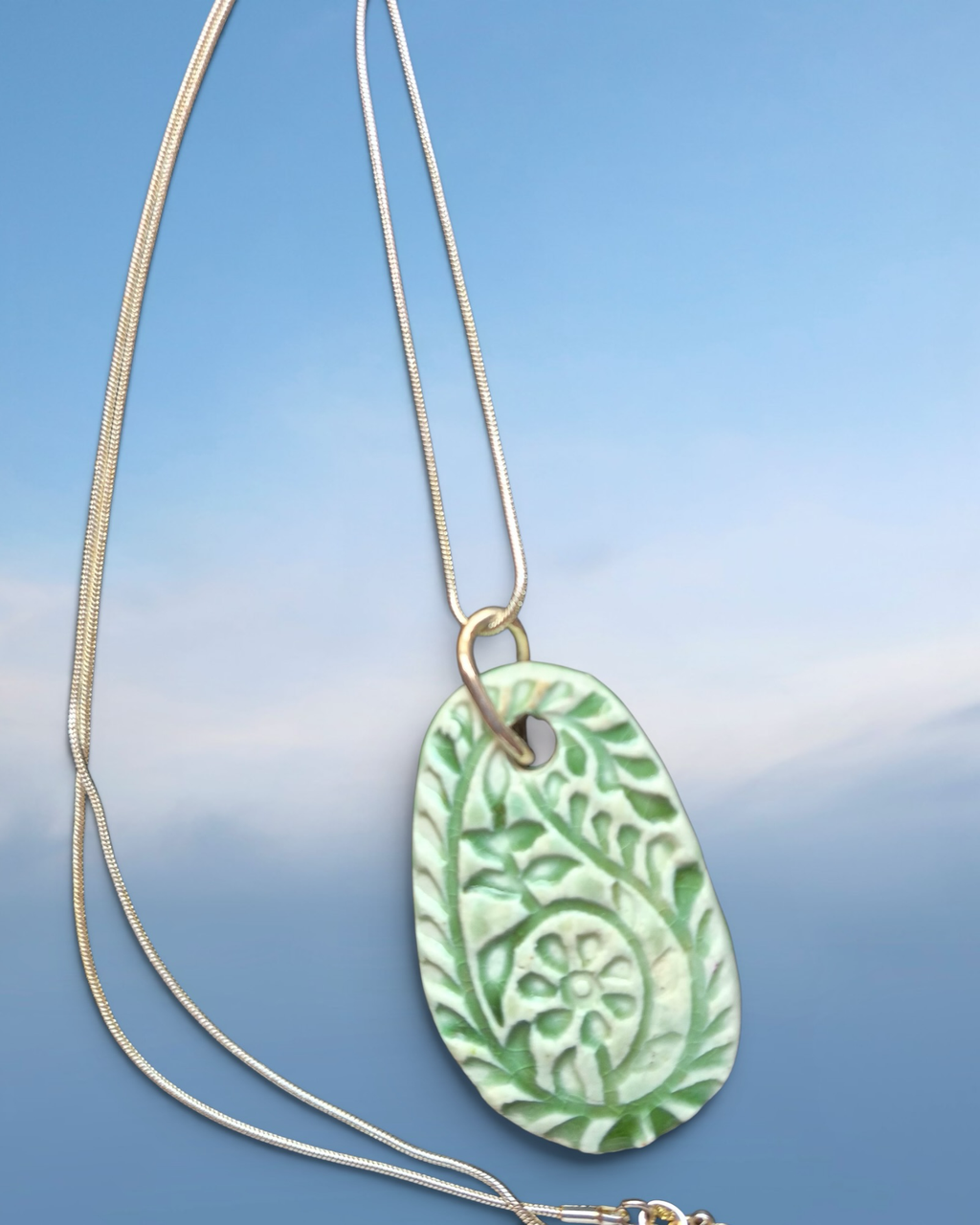 Heartfelt Creations sage-green ceramic pendant necklace with embossed botanical floral design on a silver-tone chain.