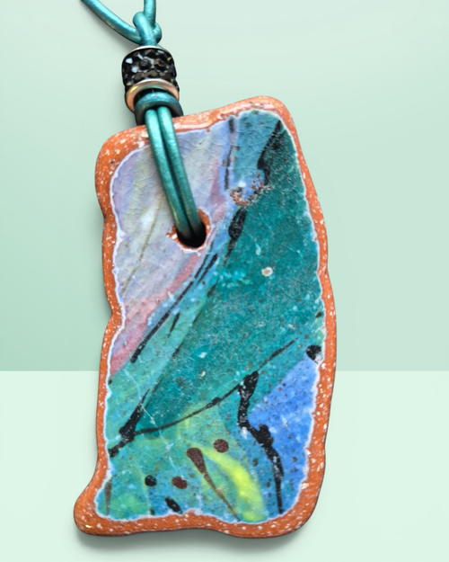 Heartfelt Creations artisan ceramic pendant necklace with crackled teal, blue, and pink glaze on a teal leather cord.