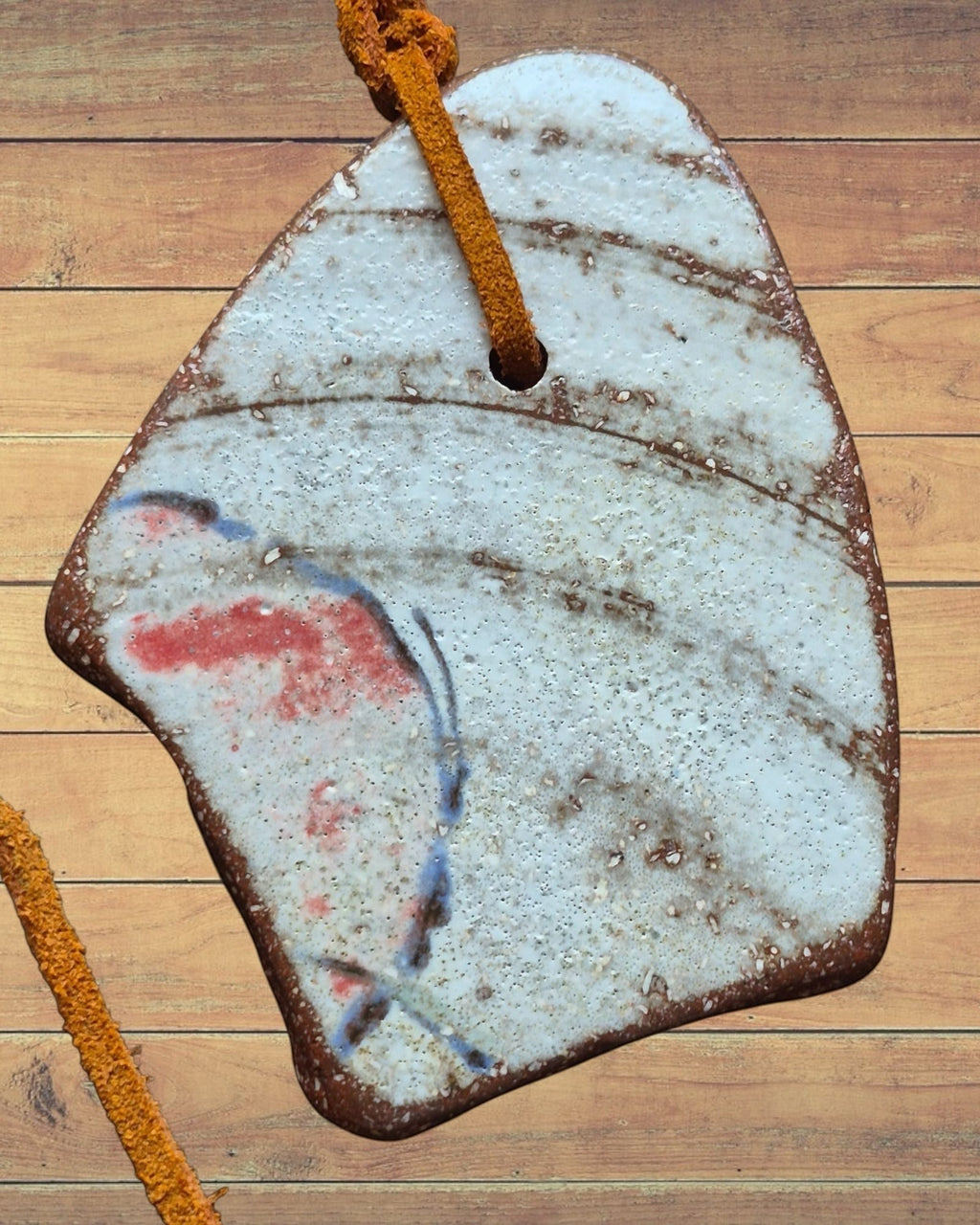 Heartfelt Creations artisan ceramic pendant necklace with rustic textured finish, red and blue accents, on leather cord