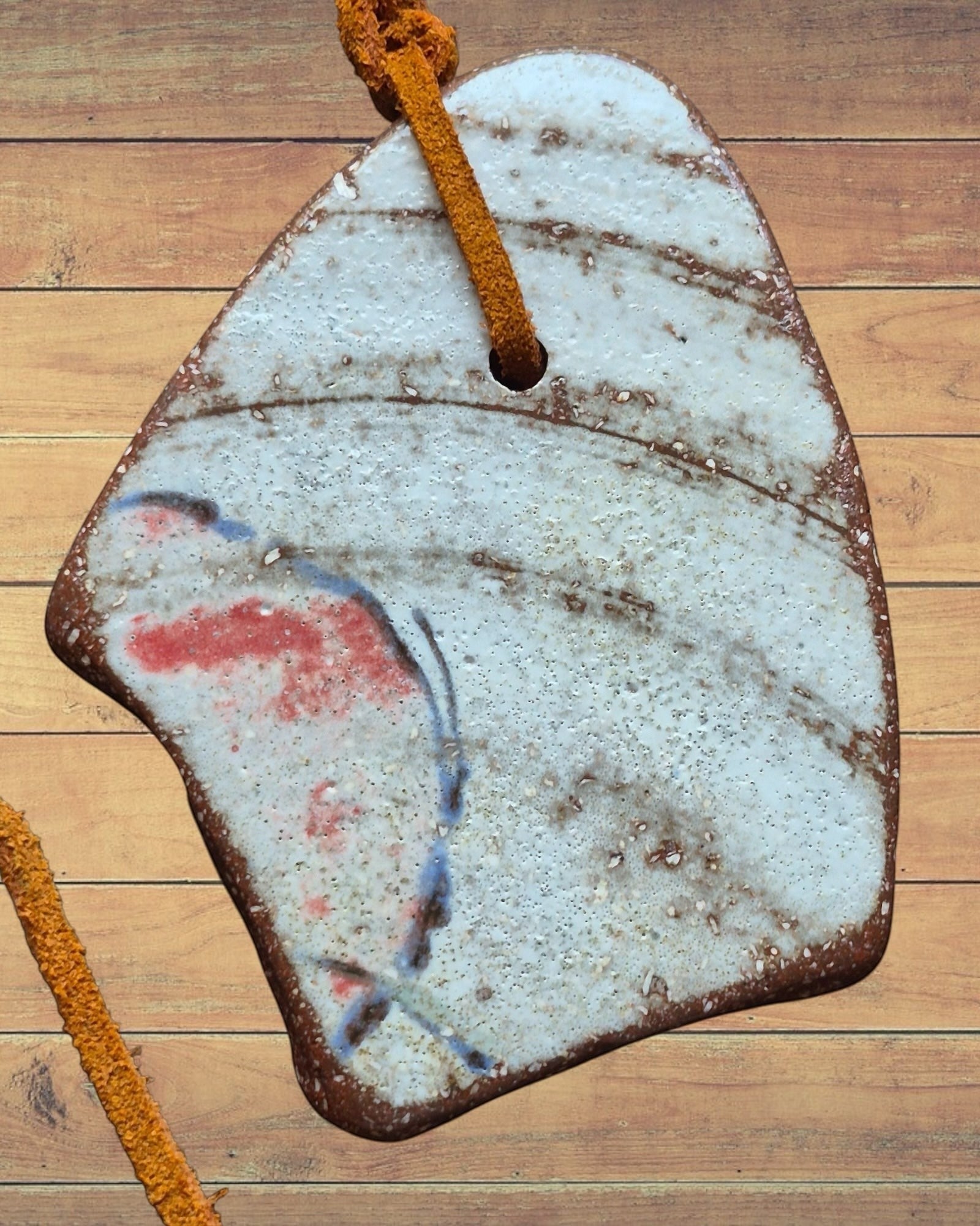 Heartfelt Creations artisan ceramic pendant necklace with rustic textured finish, red and blue accents, on leather cord